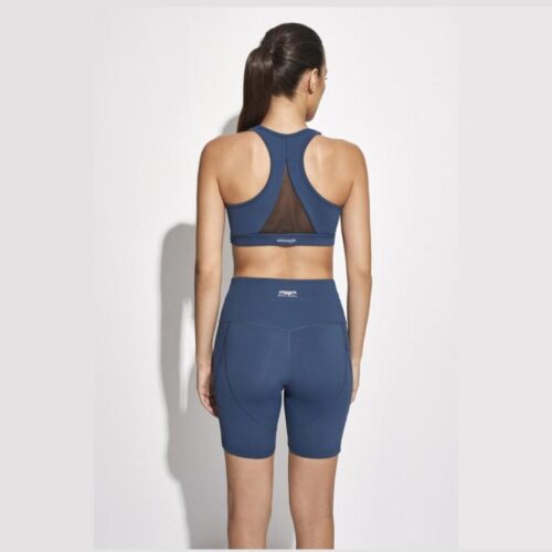 Una mujer de espaldas con unos shorts y top deportivos de color azul marino